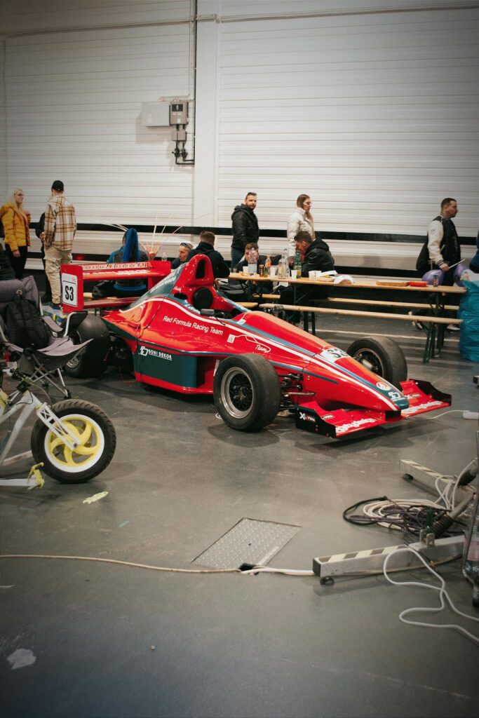 Red Formula 1 car in a garage with people, showcasing the racing scene in Hungary.