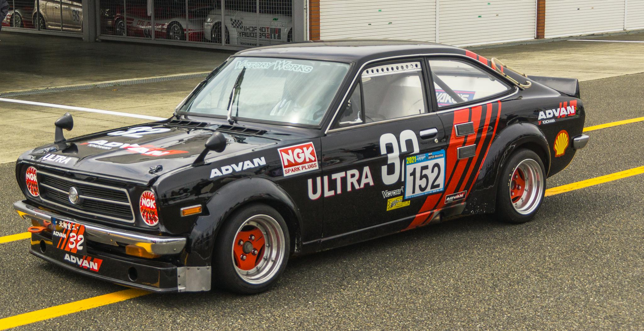 Classic black race car parked at the pit lane, showcasing retro design and vibrant graphics.