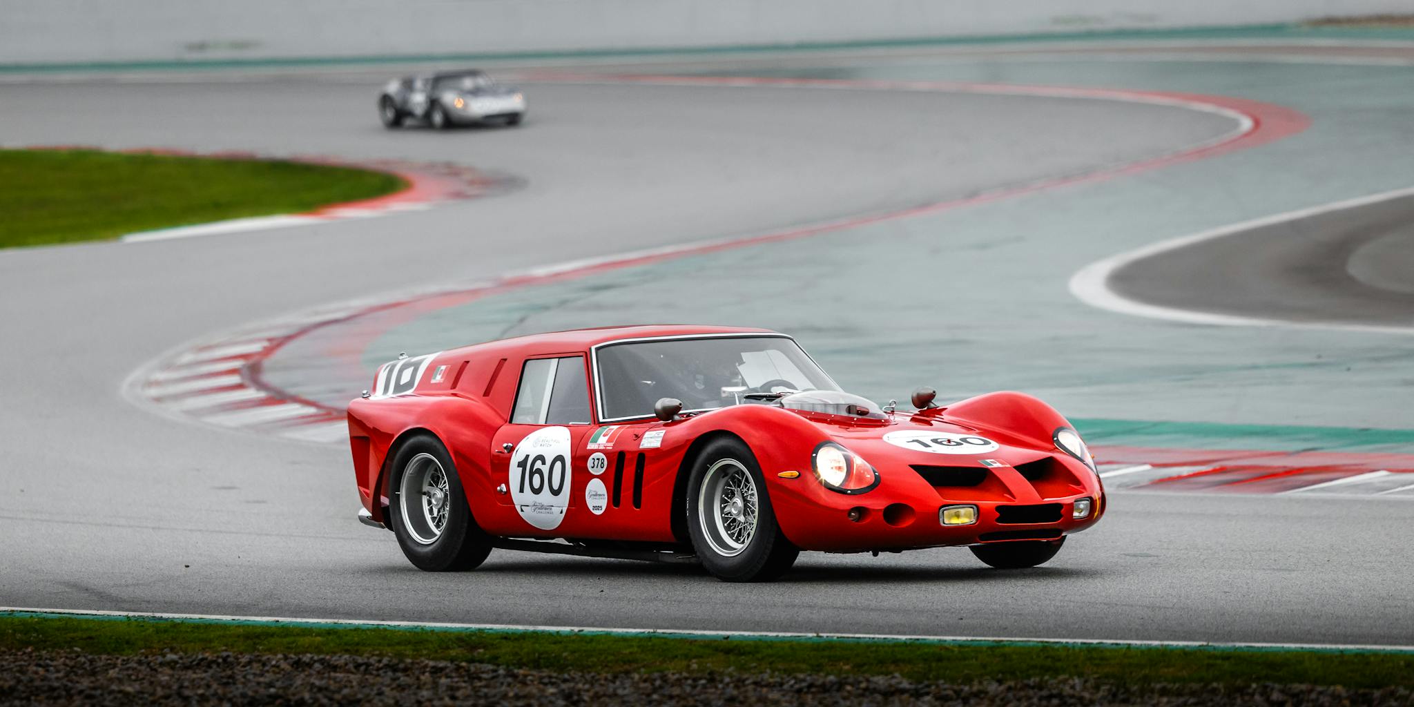Red vintage racing car navigating a track curve during a race.